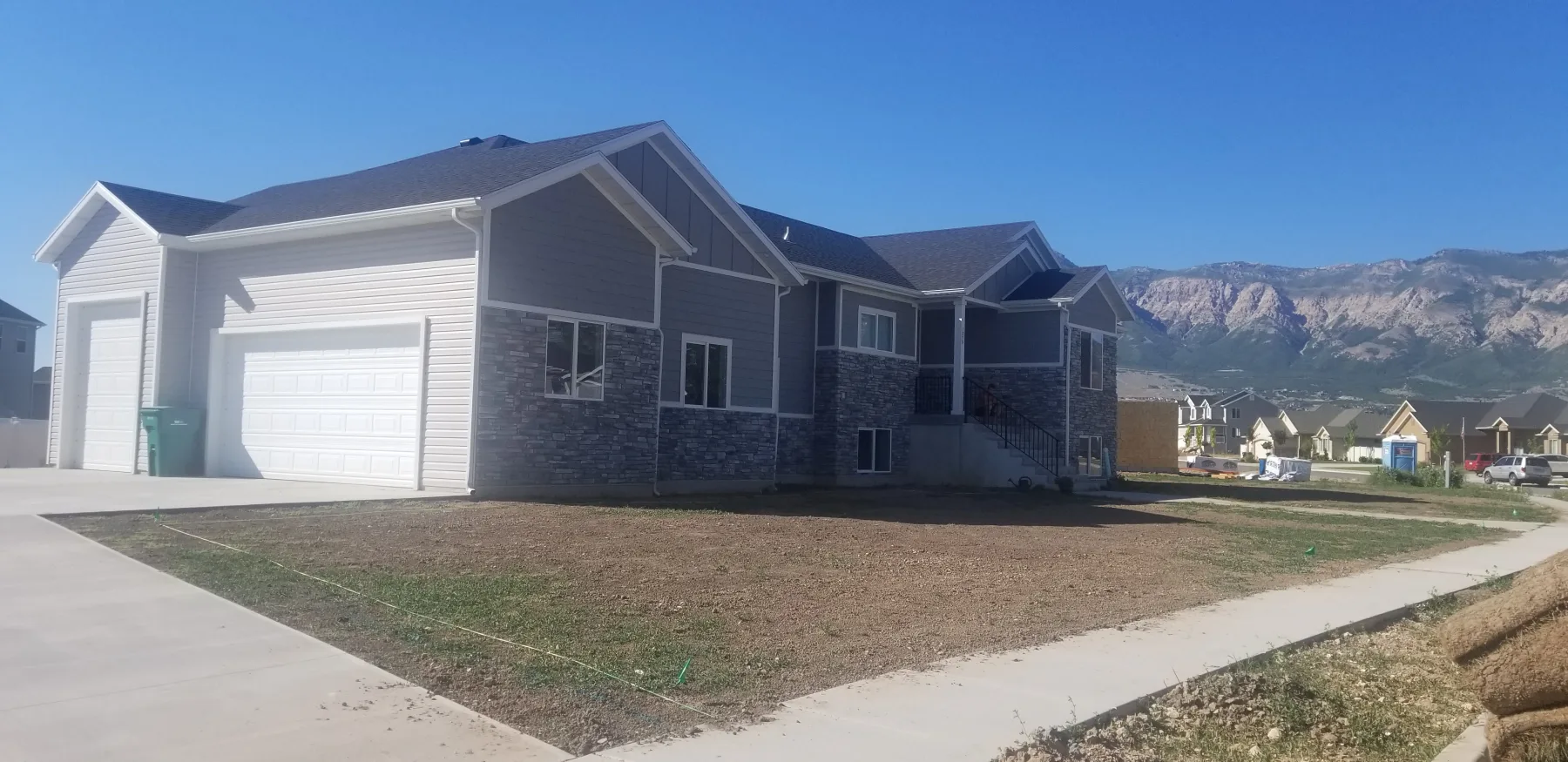 Architectural shingles on a gray home with stone siding and mountains in the background